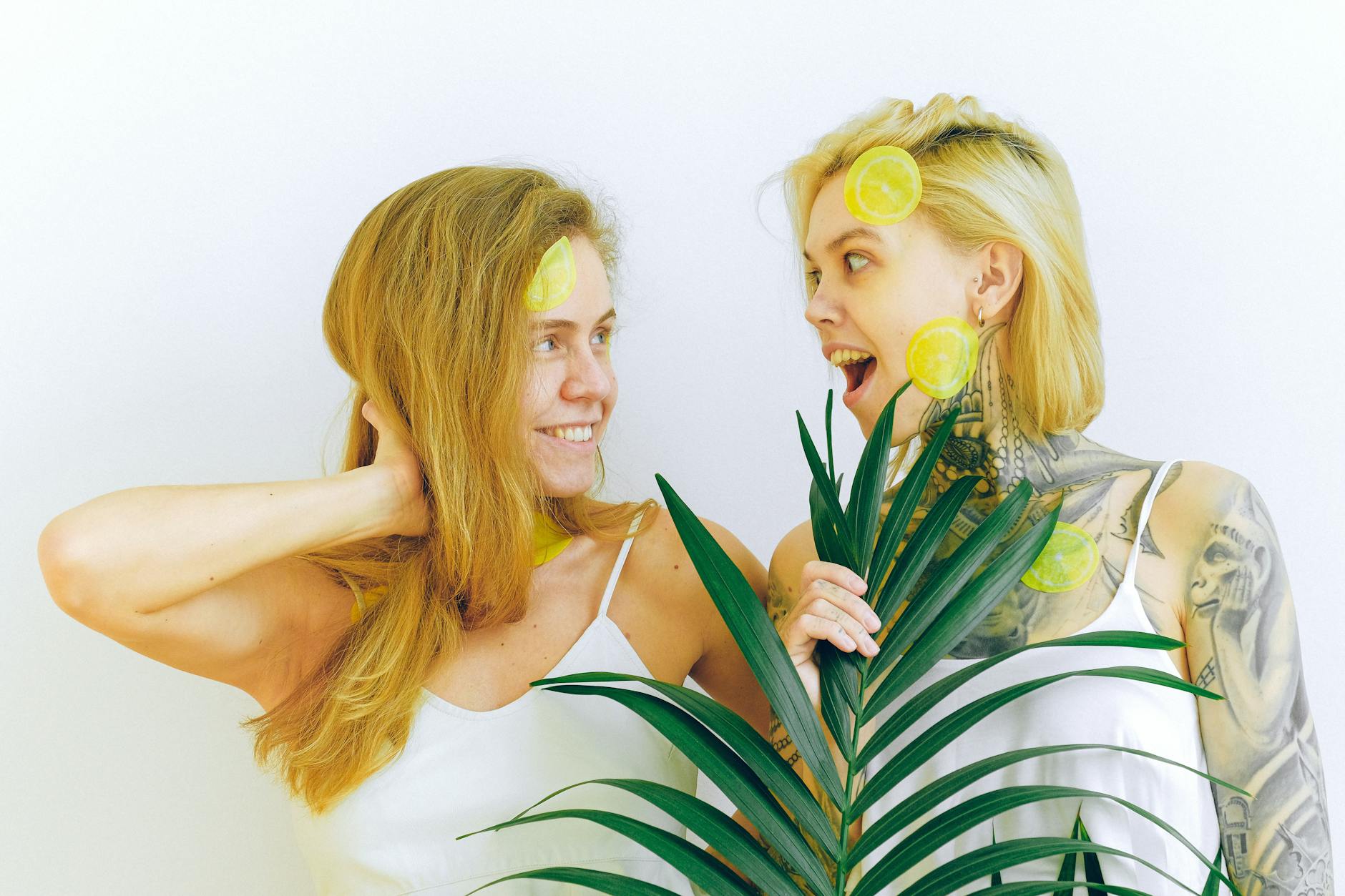 Two women smiling and enjoying citrus fruit indoors, expressing joy and shared pleasure