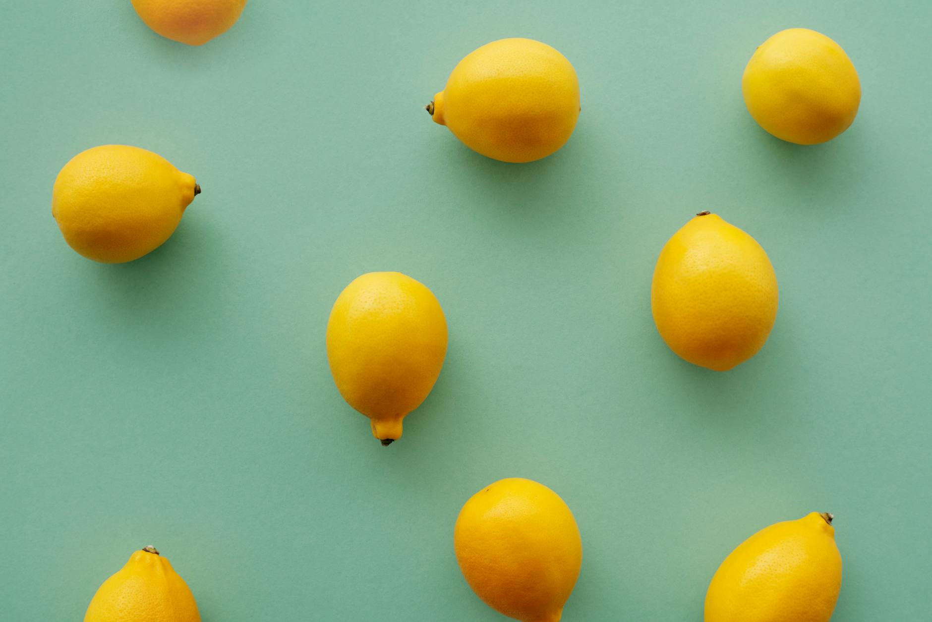 Bright yellow lemons arranged on a pastel green background, symbolizing postpartum freshness and renewal.