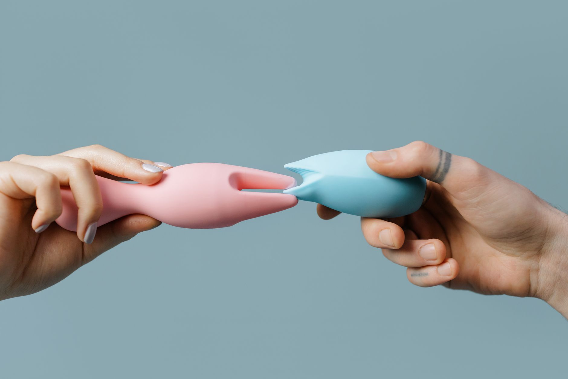 Hands holding colorful silicone vibrators for intimate play