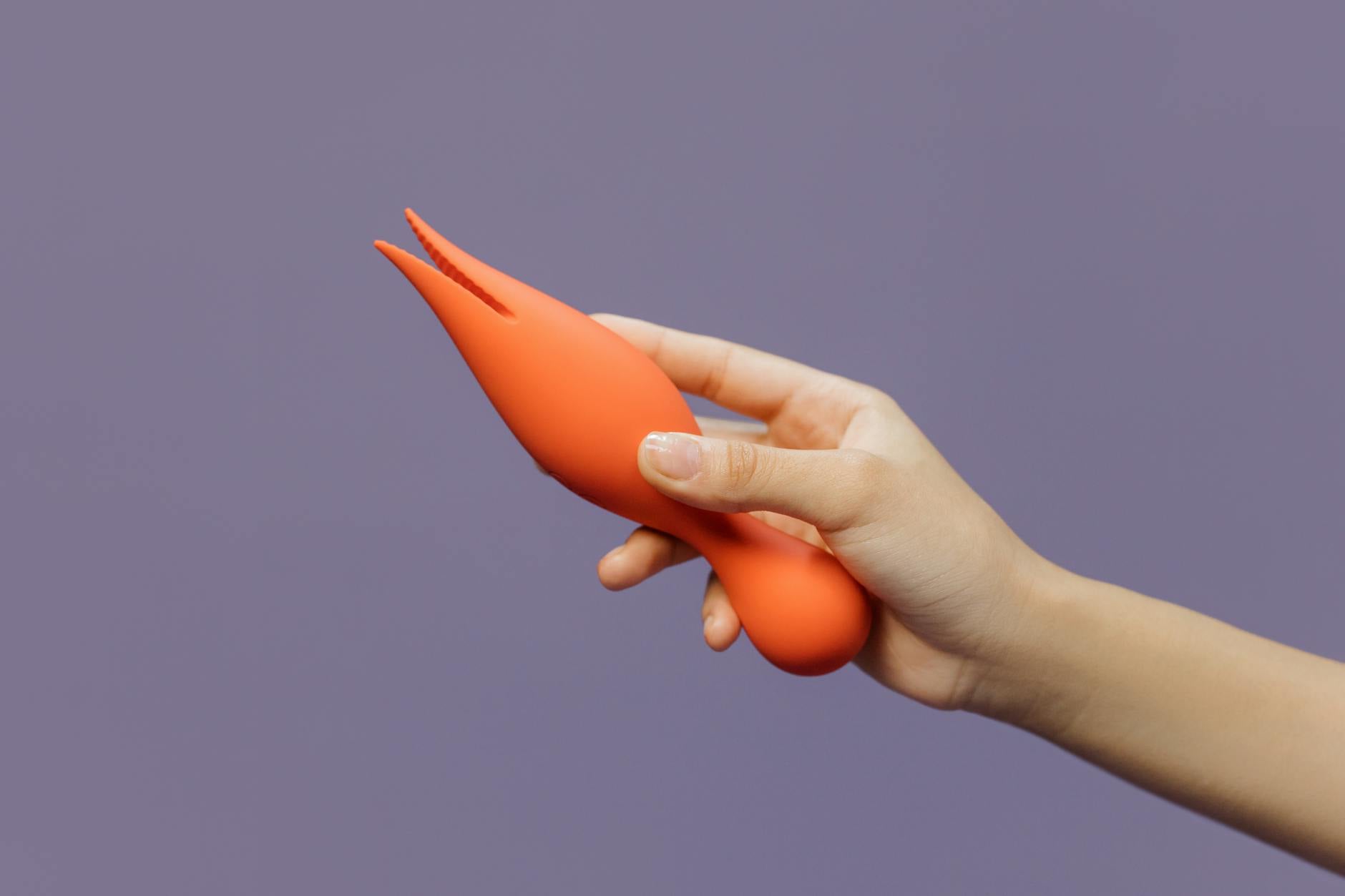 A hand holding a lemon-colored vibrator against a minimalistic purple backdrop, symbolizing reconnection and sensual awakening.