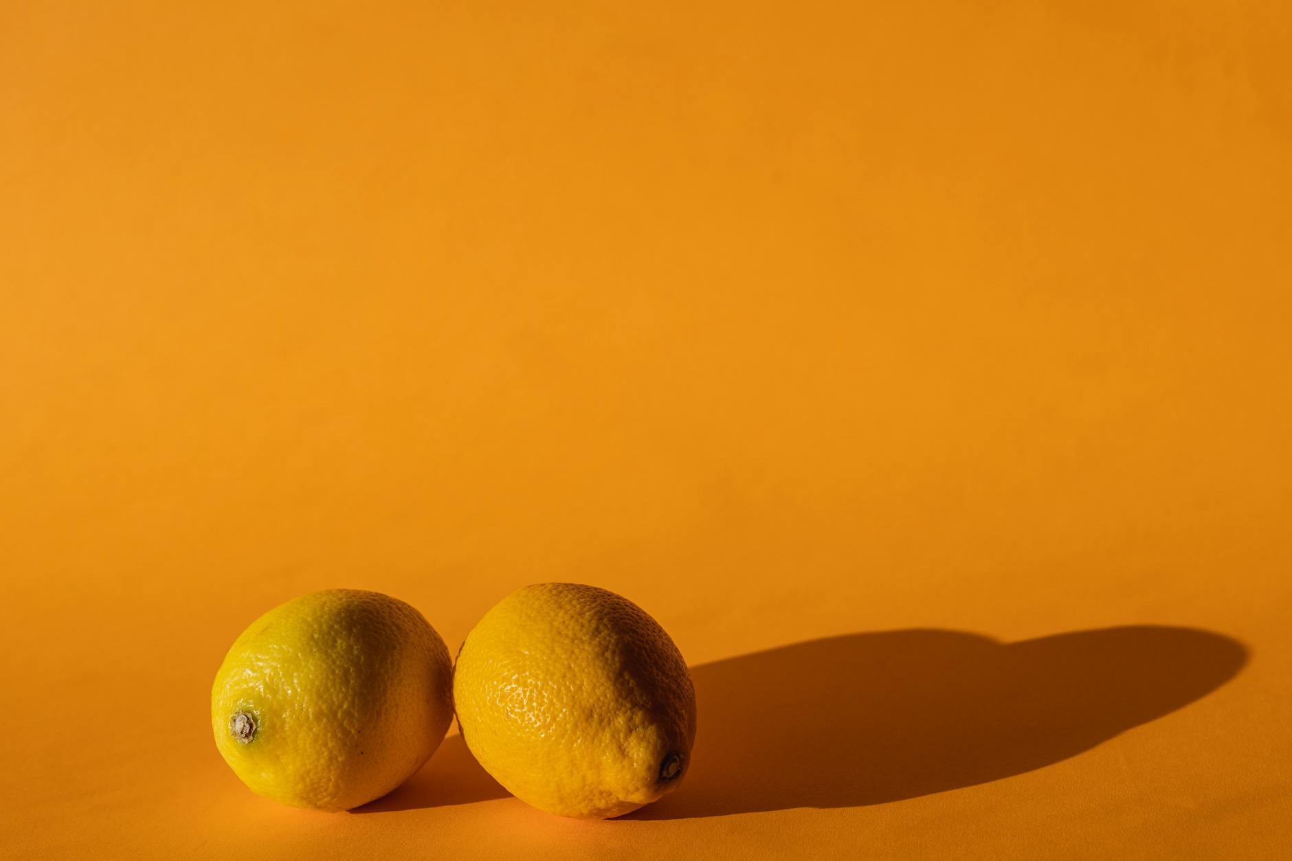 A yellow silicone clitoral vibrator surrounded by tropical elements on a soft background